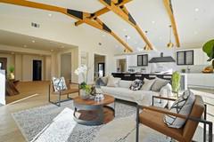 Living room with exposed beams, sitting area and open-plan kitchen with parallel island